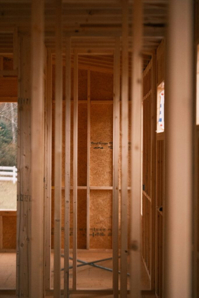 Charpente intérieure en bois d’une maison en construction, montrant les montants verticaux en pin clair.
